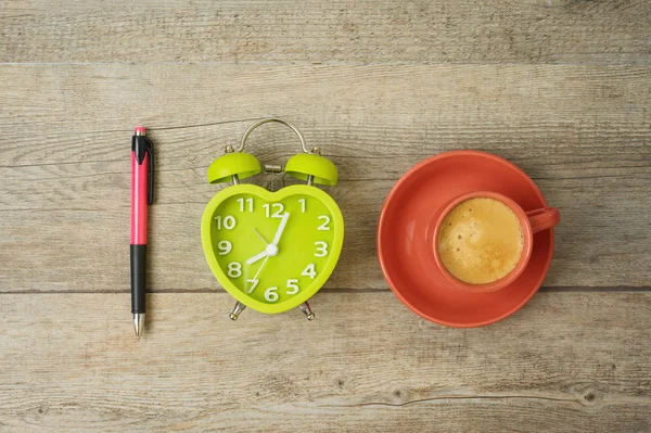 Kaffepaus. Kaffekopp, väckarklocka och penna på trä — Stockfoto