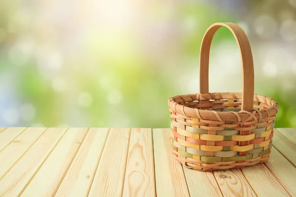 Empty basket on wooden table over green bokeh background. Spring — Stockfoto