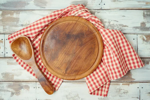 Кругла дошка для піци з червоною перевіреною скатертиною на сільському дерев'яному т — стокове фото