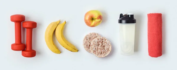 Fitnesskonzept mit Kurzhanteln, Proteinshake, Früchten und Handtuch — Stockfoto