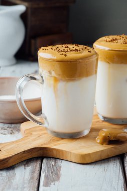 Dalgona kahvesi ya da ahşap masada sütlü kremalı kahve.