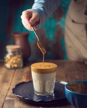 Dalgona kahvesi ya da ahşap masada sütlü kremalı kahve.