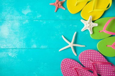 Mavi tahta üzerinde parmak arası terlikleri olan yaz arkaplanı. Yukarıdan üst görünüm