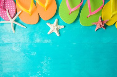 Mavi tahta üzerinde parmak arası terlikleri olan yaz arkaplanı. Yukarıdan üst görünüm