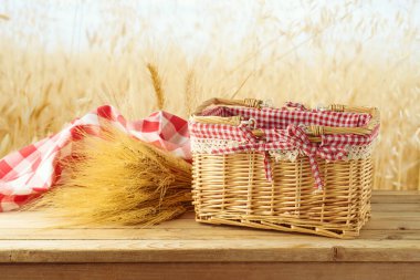 Boş piknik sepeti, buğday ve kırmızı masa örtüsü, buğday tarlasının arka planında, ahşap masa örtüsü. Tasarım için biçin.