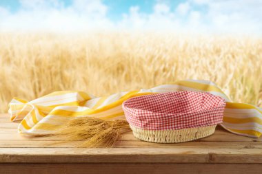 Boş sepet içinde buğday ve masa örtüsü olan tahtadan masa örtüsü buğday tarlasının arka planında. Tasarım için biçin.