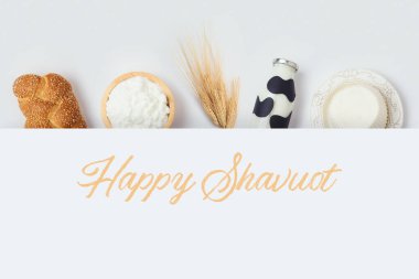 Yahudi bayramı Shavuot pankartı, beyaz arka planda süt şişesi, peynir ve ekmek tasarımı. Yukarıdan üst görünüm
