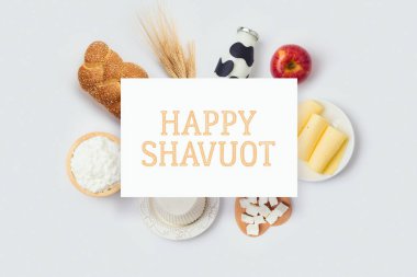 Yahudi bayramı Shavuot pankartı, beyaz arka planda süt şişesi, peynir ve ekmek tasarımı. Yukarıdan üst görünüm