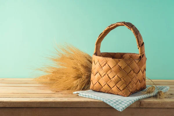 Empty basket with wheat on wooden table over blue background. Harvest mock up for design.