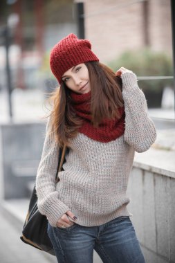 Sıcak bir kazak, kırmızı bere ve atkı ve bir sırt çantası onun omuz üzerinde güzel bir genç kız portresi