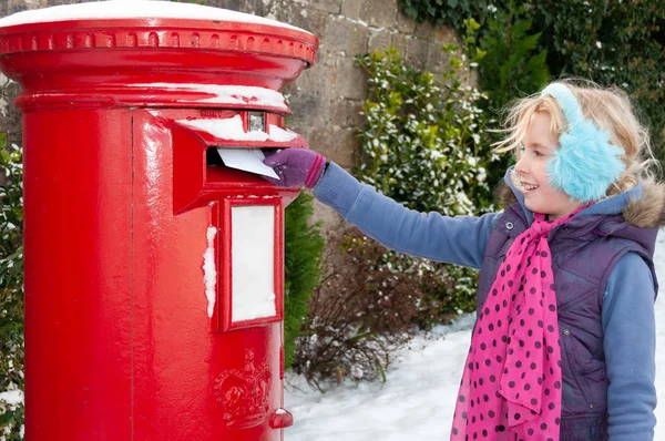 Young blonde girl in blue ear muffs posting her letter to Santa — Stock Photo, Image