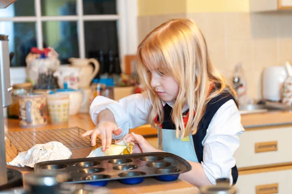 Junges blondes Mädchen benutzt Butter beim Backen in einer unordentlichen Küche — Stockfoto