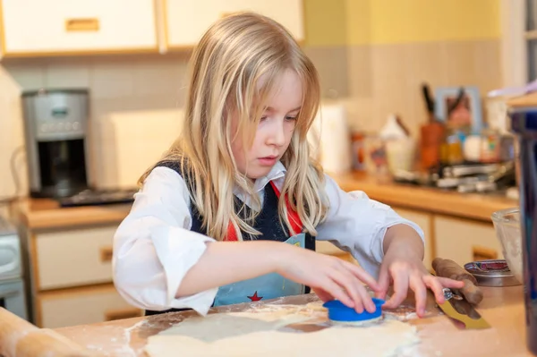 Hübsche junge blonde Mädchen beim Backen in einer chaotischen Küche Teig ausschneiden — Stockfoto