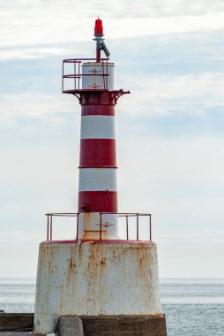 İskelenin sonundaki paslı, eski, kırmızı ve beyaz çizgili deniz fenerini kapatın.
