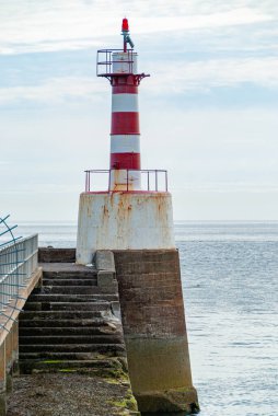 İskelenin sonundaki paslı kırmızı ve beyaz çizgili deniz feneri.