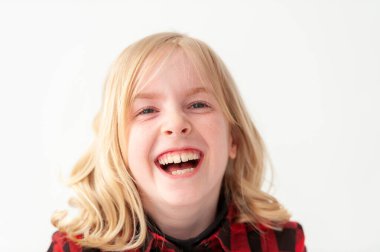 Beyaz bir stüdyoda gülen genç sarışın bir kızın vesikalık fotoğrafı.