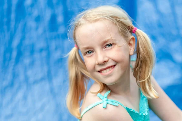 Smiling young girl with pigtails on a blurry blue background — Stock Photo, Image