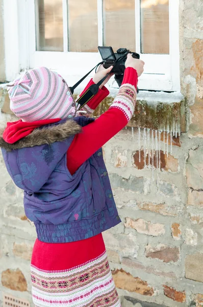Young girl taking an overhead photograph of icicles hanging from a stone window ledge — Stock Photo, Image