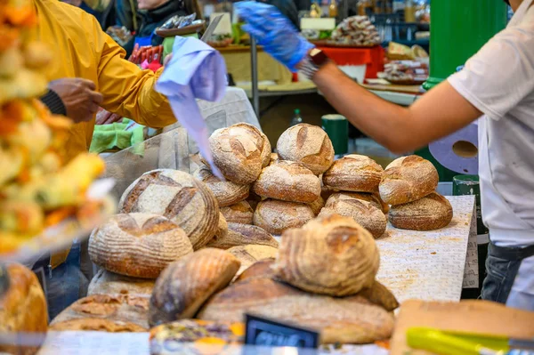 Un tendero interactuando con los clientes en un puesto de pan en Borough Market, Londres — Foto de Stock