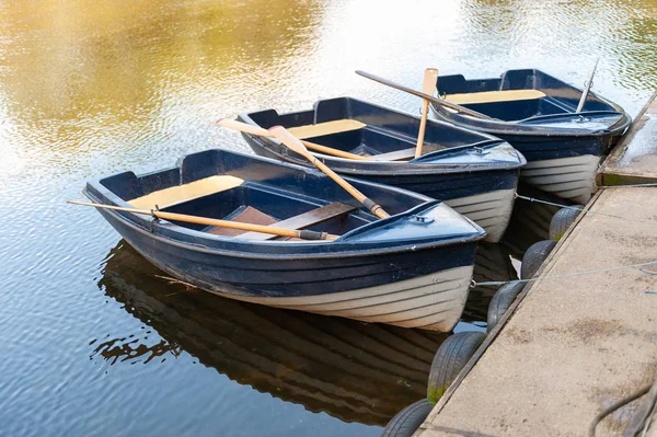 Close up de três barcos a remo azuis e brancos ancorados em um rio tranquilo em um dia ensolarado — Fotografia de Stock