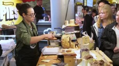 Londra - 27 Eylül 2019: Londra 'daki Borough Market' te bir peynir dükkanında bedava peynir tadımcısı sunan kadın bir sokak yemeği satıcısı.