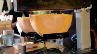 Geleneksel Cheese Raclette Borough Market, Londra 'da bir sokak yemeği dükkanında. Yukarıdaki alevlerin altında eriyen peynirin yarım tekerleklerini görmek.
