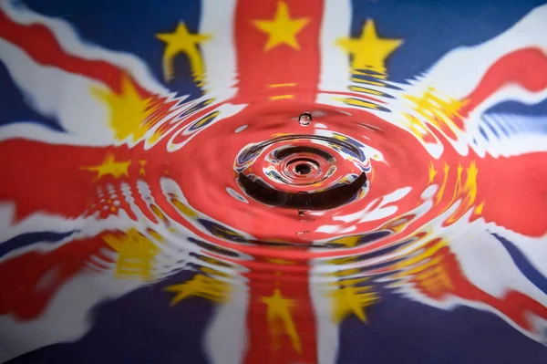 UK Union Jack and the stars of the European Union reflected in a water splash with a single drop of water falling