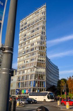 Önünde trafik varken spor salonu olan uzun bir ofis bloğu.