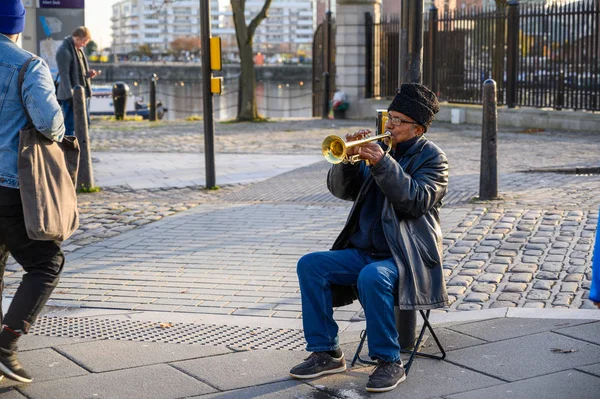 Un busker tocando una trompeta en un día frío pero soleado — Foto de Stock