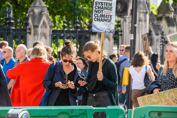 Manifestantes da Mudança Climática usando smartphones e segurando cartazes de protesto em uma manifestação da Rebelião de Extinção — Fotografia de Stock