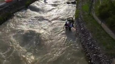 BRATISLAVA, SLOVAKIA - CIRCA  AUGUST, 2017: A Slalom Kayak paddler passes three kids playing in white water