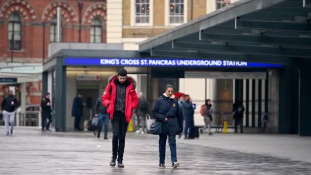 ロンドン 2020年3月19日 明るい赤いコートを着た男が 駅の外にあるキングス クロス スクエアの女性の隣を歩いている 散歩中に彼を追いかける — ストック動画