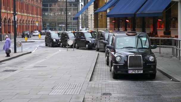 2020年3月19日 一辆黑色伦敦出租车从国王十字街 King Cross Pancras 火车站外一排等候的黑色出租车旁驶离 — 图库视频影像