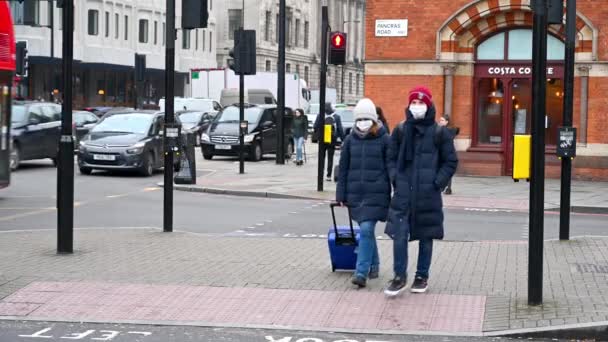 ロンドン 2020年3月19日 コロナウイルス流行中にPpeフェイスマスクを着用し キングスクロス鉄道駅の外のパンクラス道路を横断する歩行者で道路を横断するカップル — ストック動画