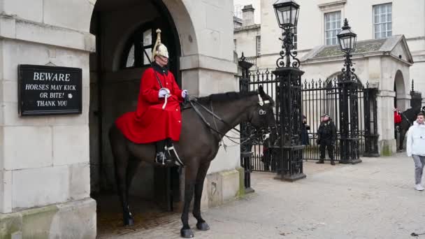 ロンドン 2020年2月3日 バックグラウンドで武装警察と馬ガードパレードの入り口に立つ騎兵世帯の騎馬警官の全長ショット — ストック動画
