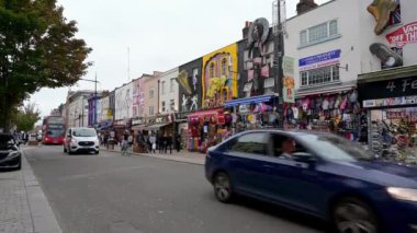 30 SEPTEMBER 2019: trafik, kırmızı bir Double Decker London otobüsü dahil, Camden High Caddesi boyunca dekore edilmiş turistik eğlence dükkanlarının önünden geçiyor. Kalabalık kaldırım müşterilerle dolu.