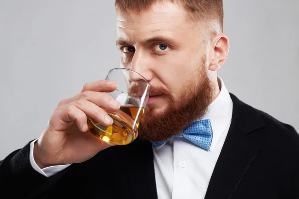 Primer plano de un hombre barbudo guapo con estilo disfrutando de un brandy o whisky — Foto de Stock