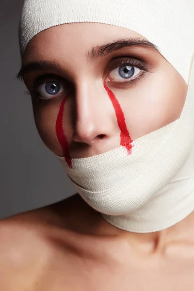 Cara femenina en bandage.girl con lágrimas sangrientas —  Fotos de Stock