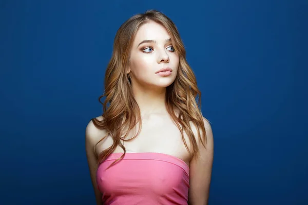 Vacker ung kvinna i rosa topp över blå bakgrund — Stockfoto