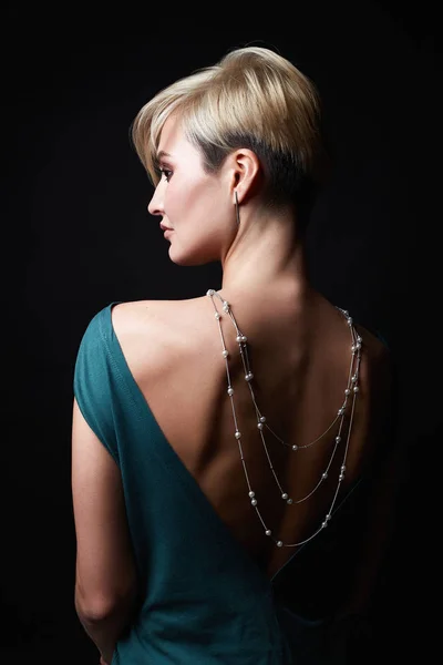 Menina de cabelo loira em vestido de noite e jóias em suas costas — Fotografia de Stock