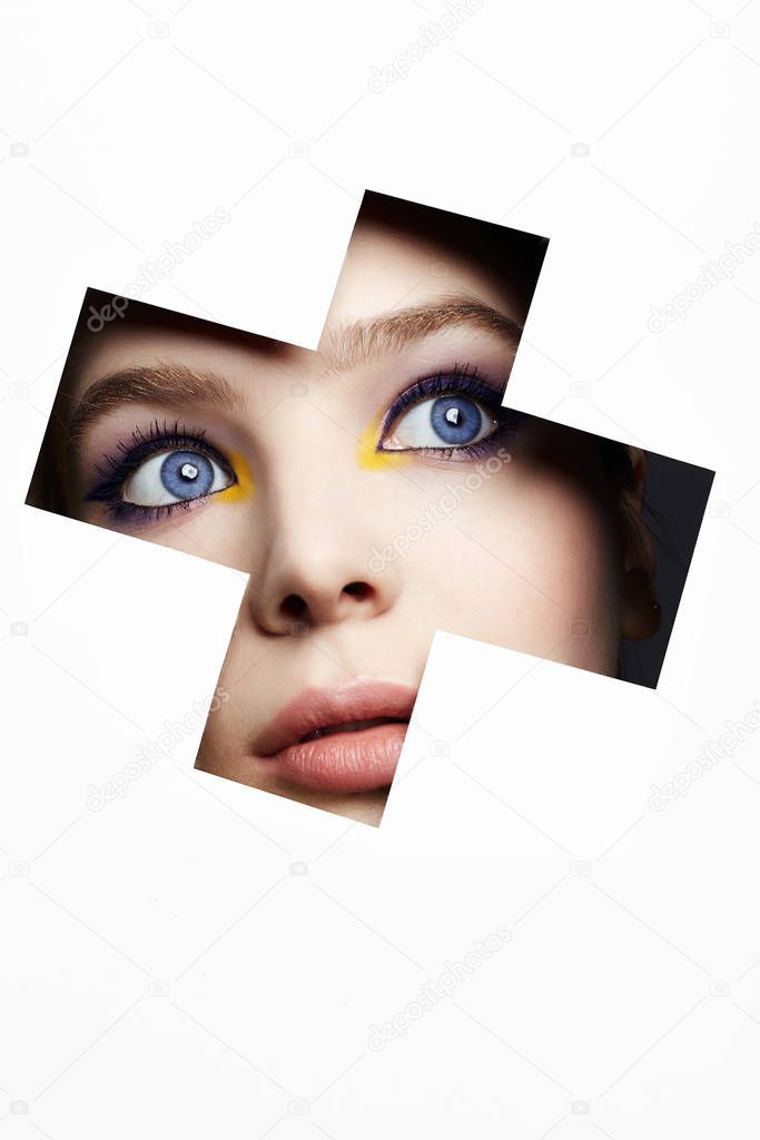 female face with color makeup into paper hole