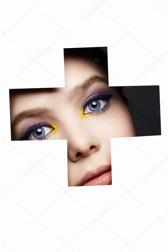 female face with color makeup into paper hole. make-up concept