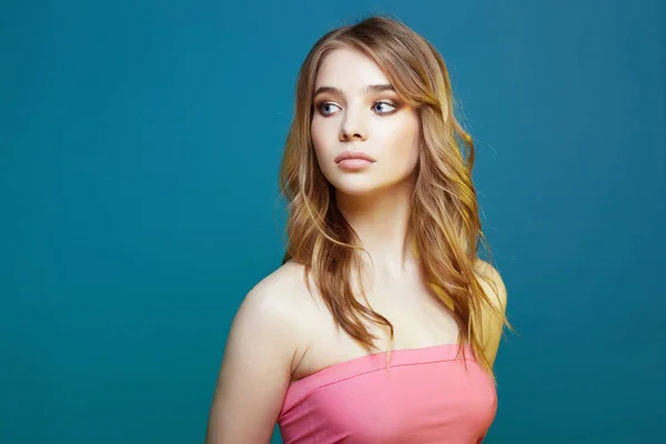 Beautiful young woman in pink top over blue background — Stock Photo, Image