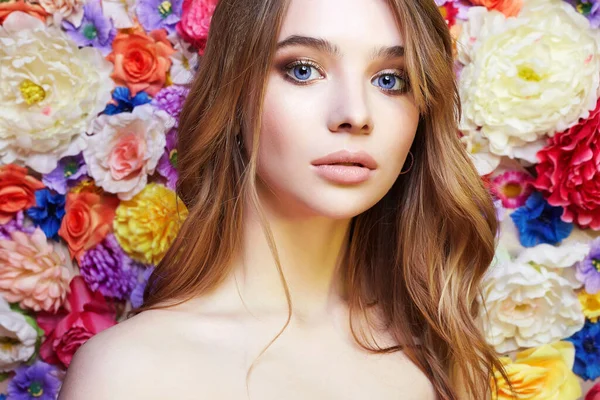 Vacker kvinna i blommor. färgglada blommig bakgrund — Stockfoto