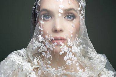 Duvağın altındaki gelinin yüzü. Güzel genç kadın.