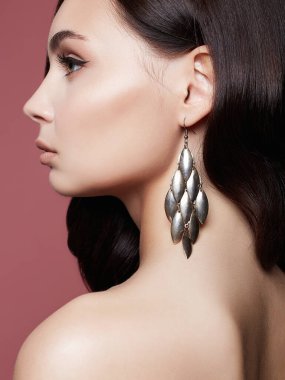 Pembe arka planda güzel bir esmer kadın. Mücevherleri olan seksi model kız. moda güzellik portresi