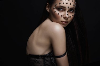 Yüzünde çelik çiviler olan güzel bir kız. Cadılar Bayramı makyajlı, iç çamaşırlı güzel seksi bir kadın. Güzellik Portresi