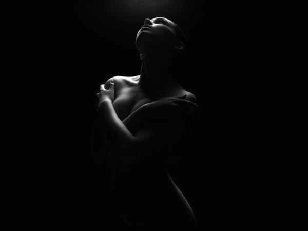 Nude Woman silhouette under light in the dark. Beautiful Sexy Naked Body Girl. Black and white
