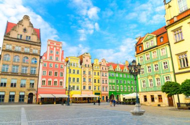 Renkli ön cepheleri ve kaldırım taşı üzerinde sokak lambası olan renkli geleneksel binalar dizisi eski kasaba tarihi şehir merkezi Wroclaw 'da Rynek Pazar Meydanı, mavi gökyüzü arka planı, Polonya