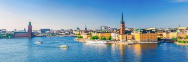 Stockholm 'ün gökyüzü manzaralı eski şehir Gamla Stan, belediye binası Stadshuset, Riddarholmen adası gotik kilise binası ve İsveç' in Malaren Gölü 'nün sularında yüzen tekne gemisi ile.